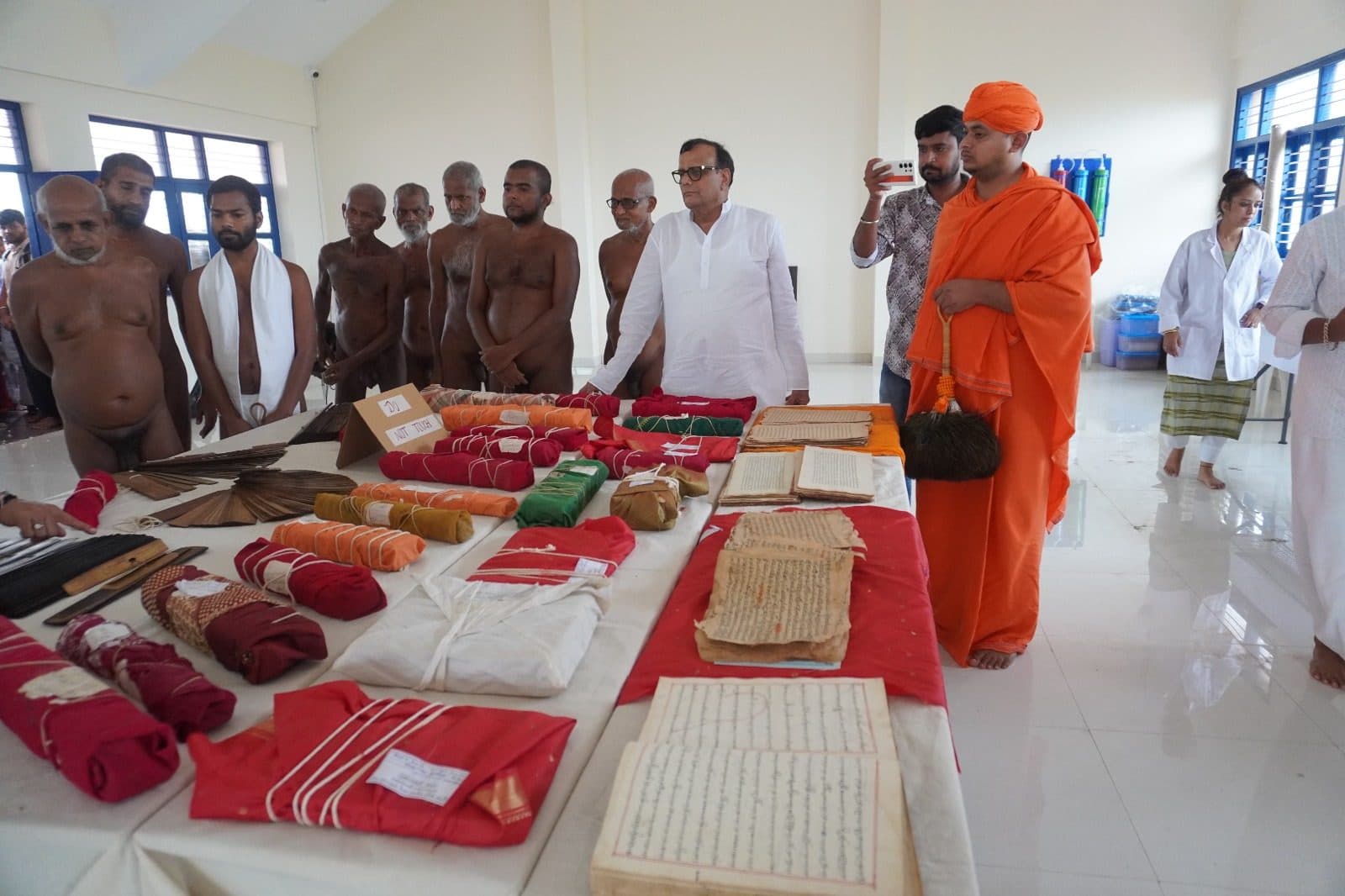 Palm-leaf bundles and cloth-wrapped manuscripts laid out in rows on red cloth.